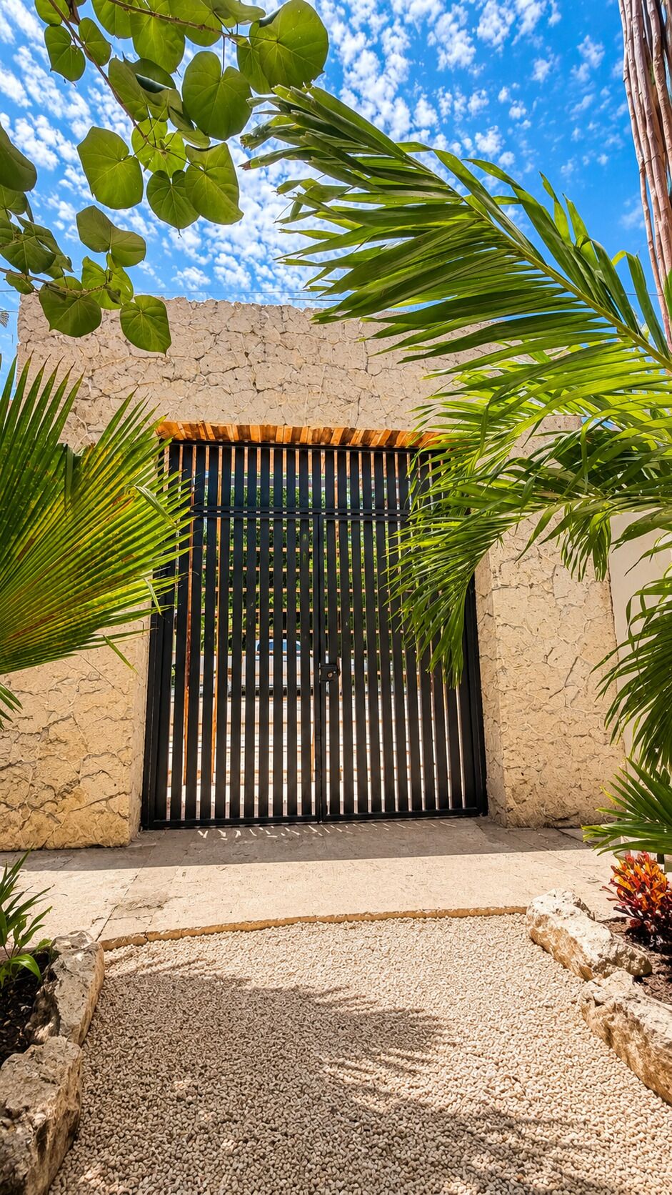 A building with a textured facade, a black gate, and surrounding greenery.