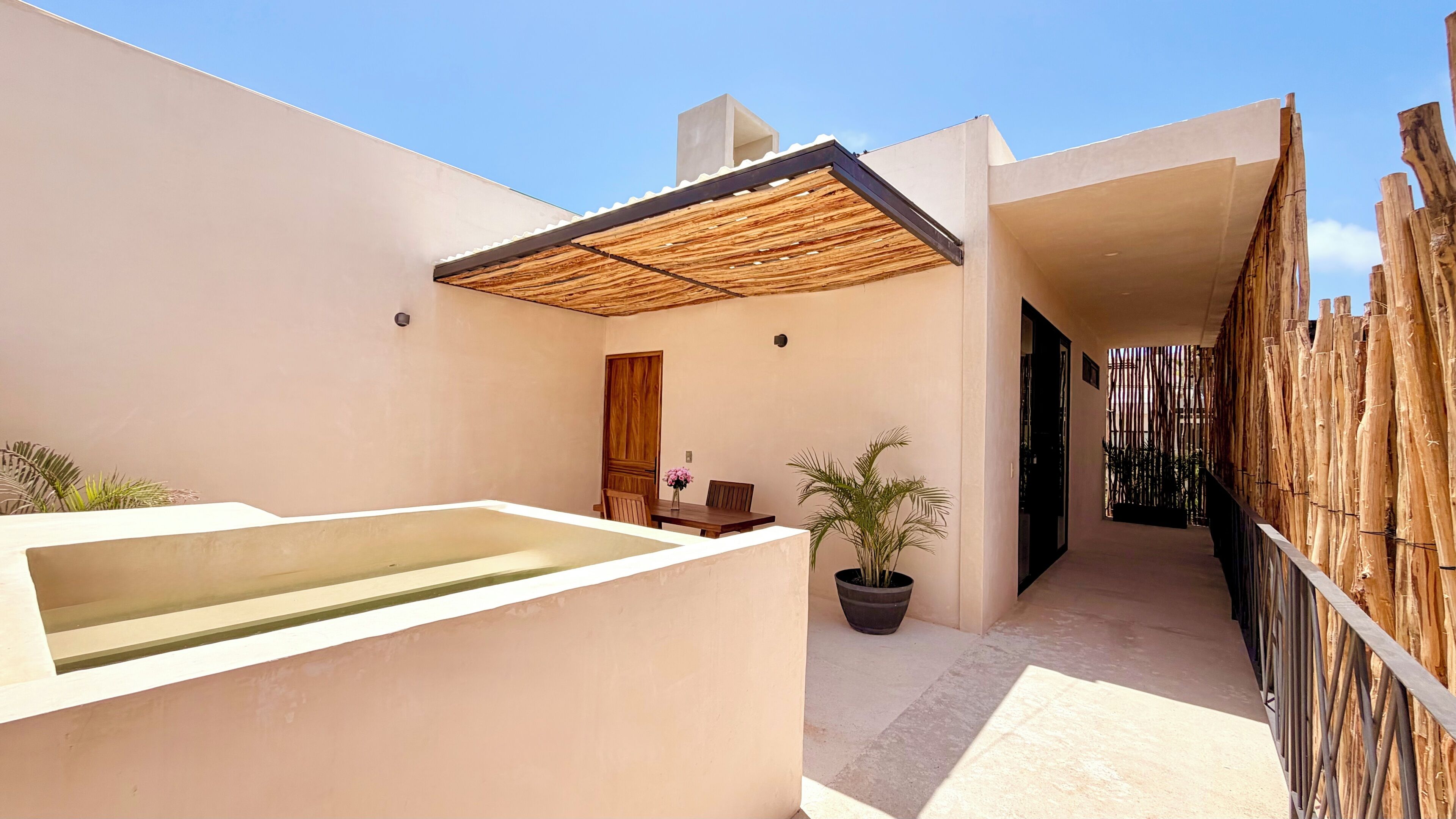 Un patio moderno al aire libre con piscina, muebles de madera y cerramiento de bambú.