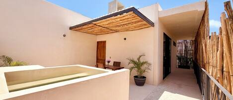 Un patio moderno al aire libre con piscina, muebles de madera y cerramiento de bambú.