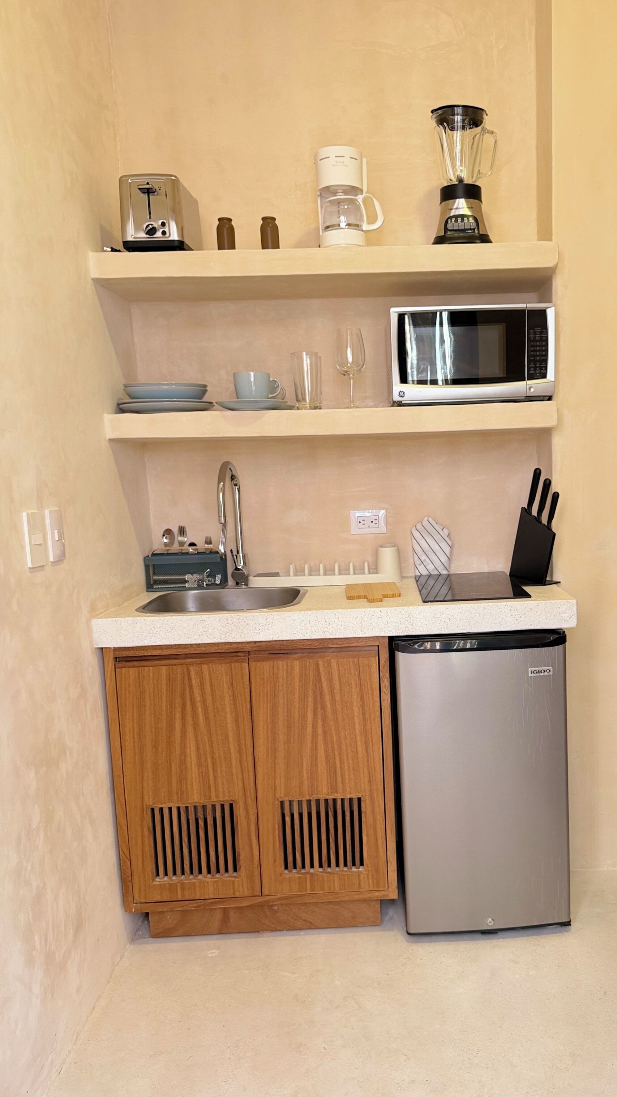 A compact kitchen with a microwave, coffee maker, blender, and a dishwasher.