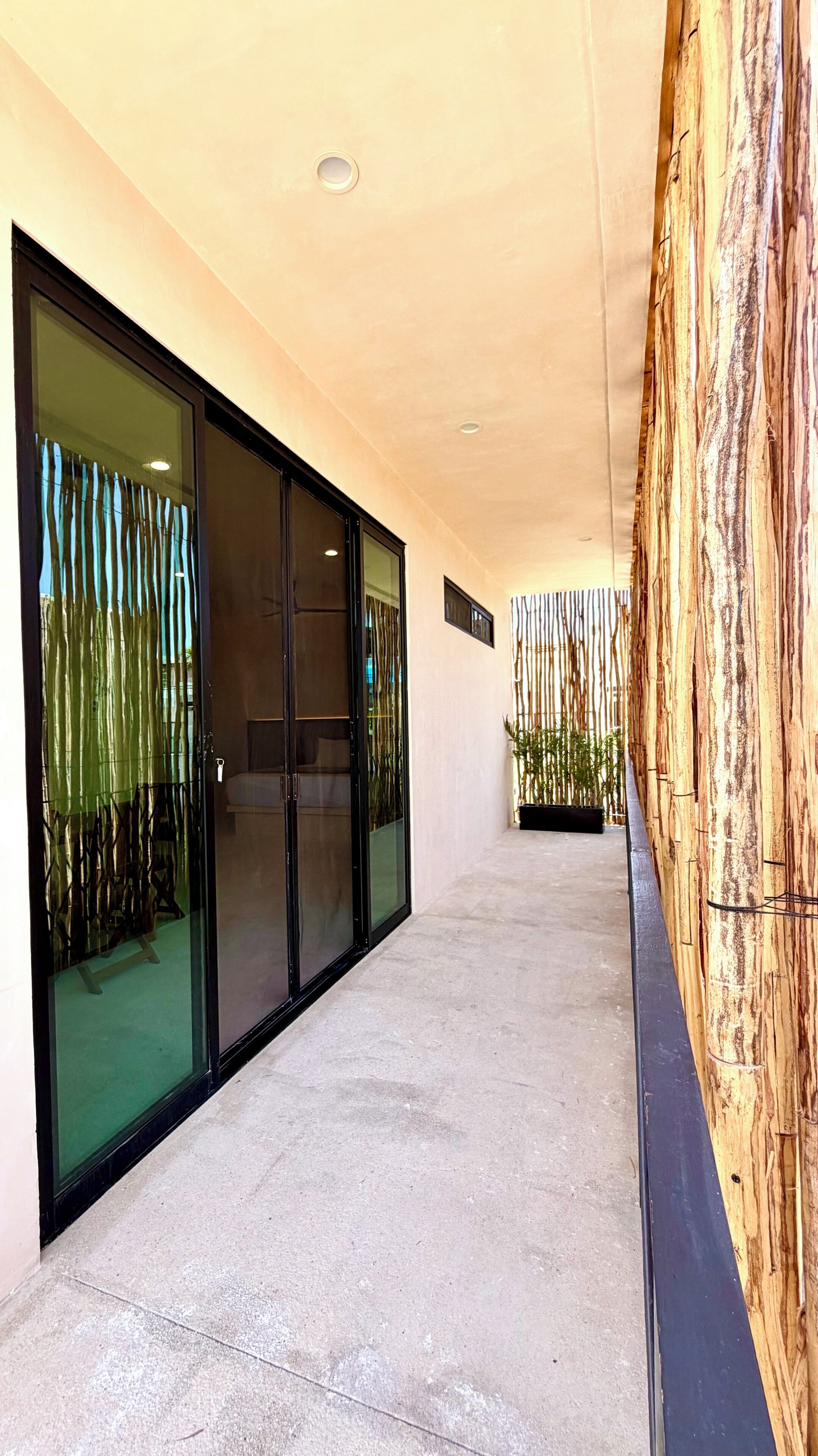 A corridor with glass doors, a concrete floor, and a wooden wall with vertical elements.