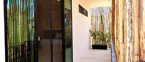 Un couloir doté de portes en verre, d’un sol en béton et d’un mur en bois avec des éléments verticaux.