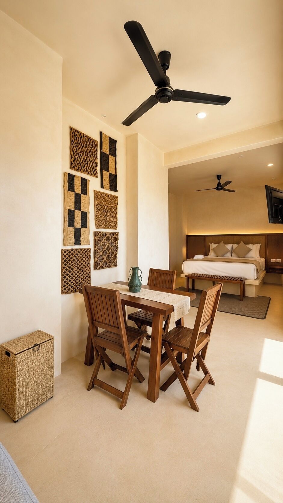 Une pièce comprenant une table à manger, des chaises, un ventilateur de plafond, un lit et des œuvres d’art décoratives murales.