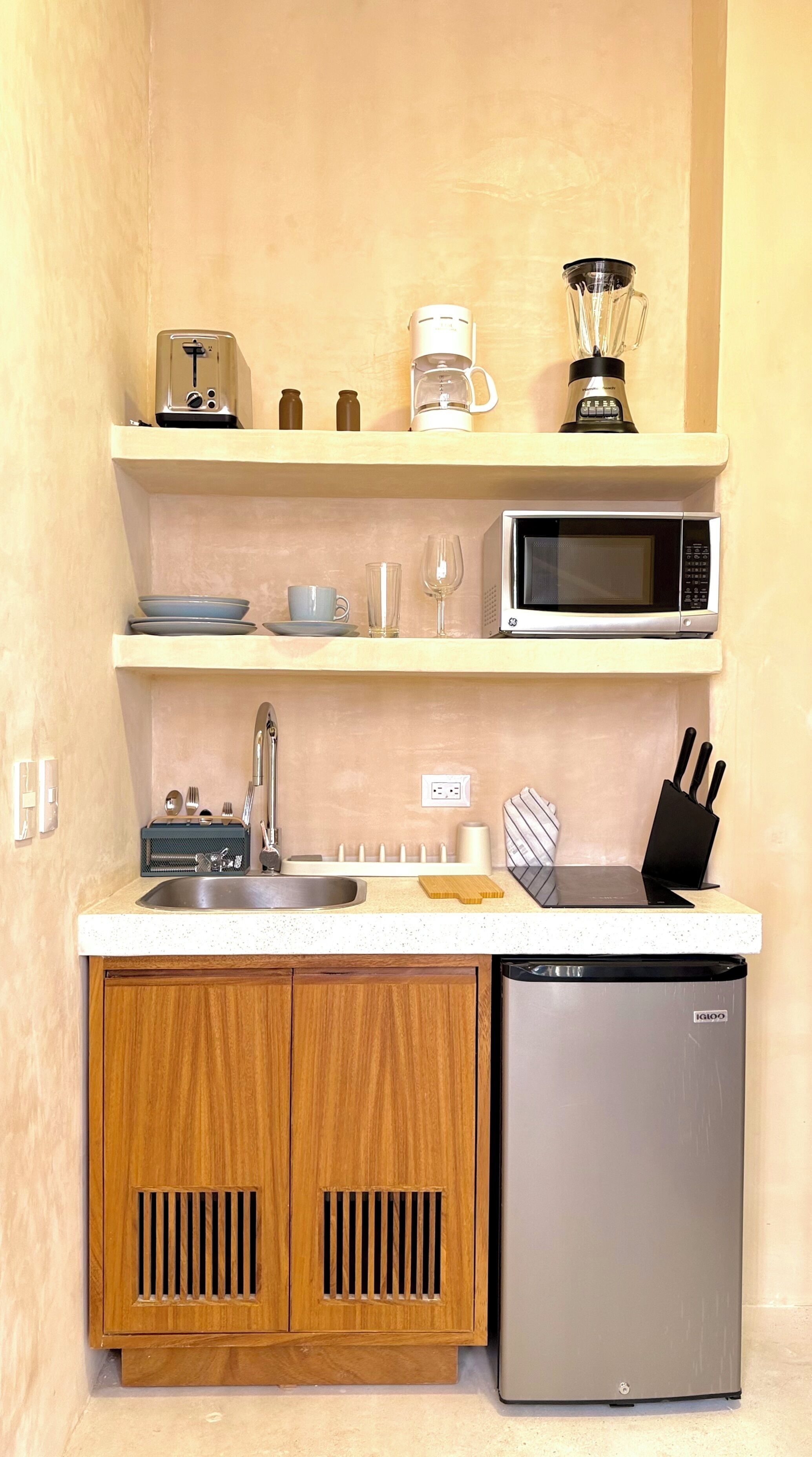 A compact kitchen with a microwave, toaster, coffee maker, and a dishwasher.