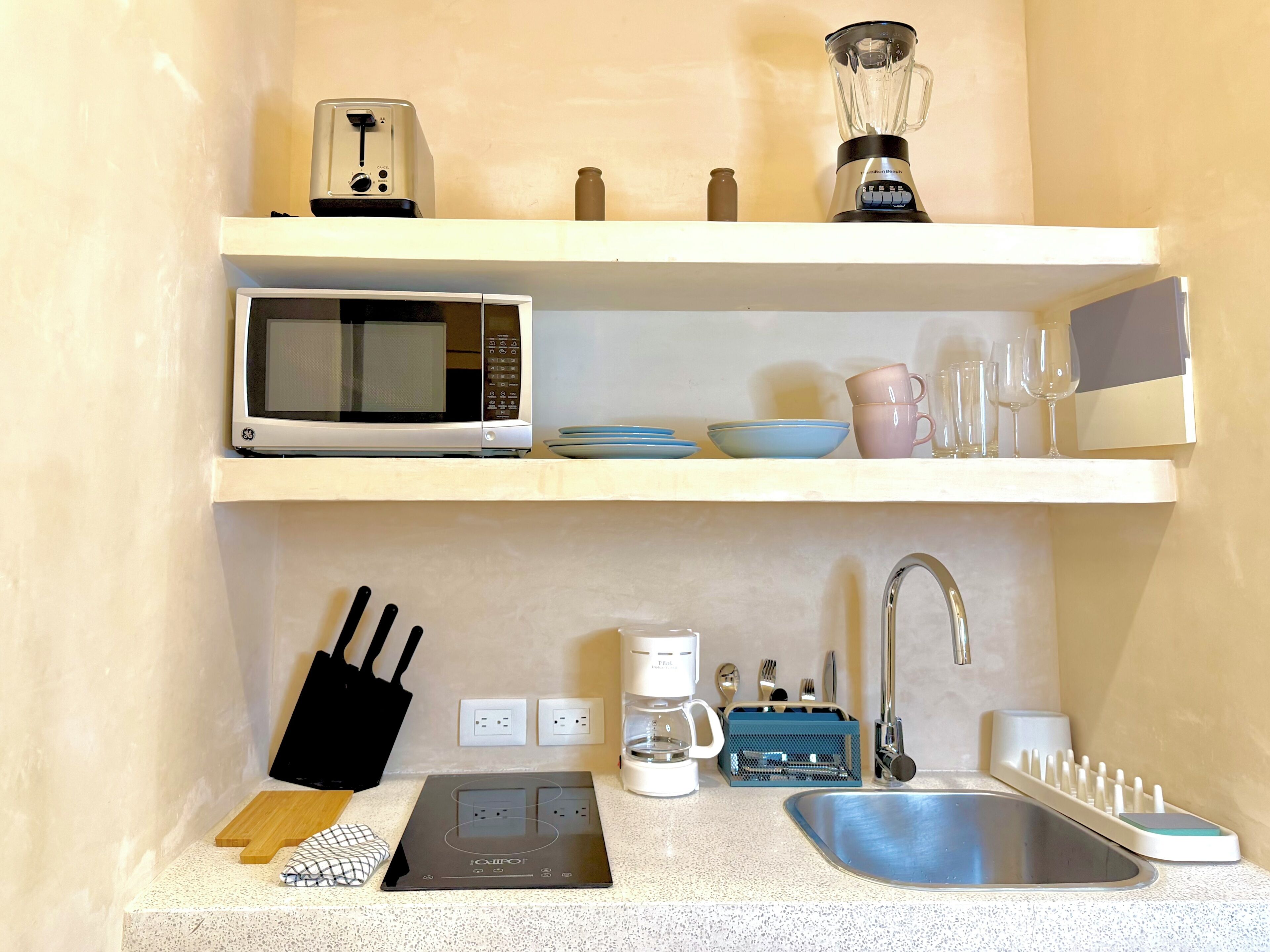 Una kitchenette equipada con microondas, tostadora, licuadora, cafetera y un lavabo.