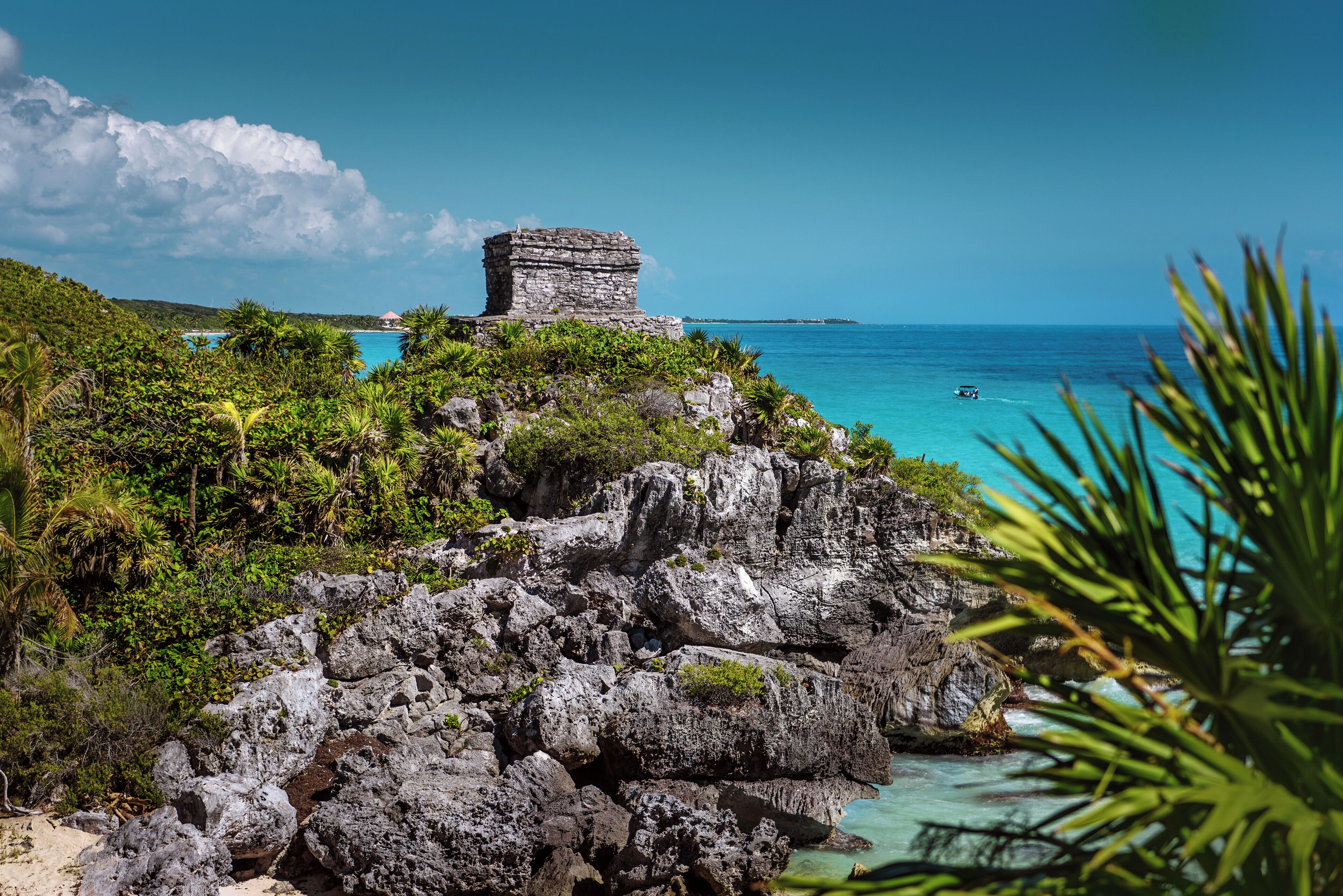 Un paysage côtier avec une structure en pierre, une végétation luxuriante et des eaux turquoise cristallines.