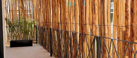 A covered walkway with a bamboo wall and metal railing.