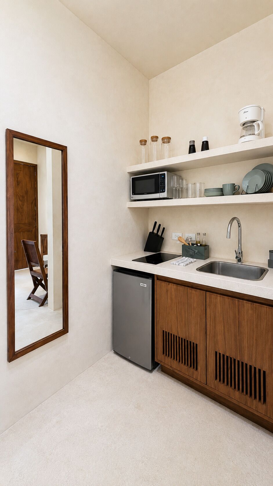 Cocina compacta con lavavajillas integrado, microondas y pileta. Hay repisas sobre la pileta con diversos objetos.