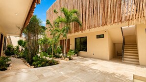 A modern building with a bamboo facade, a stone pathway, and tropical plants. -  Lapso At Tulum (Tulum)