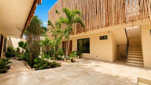 A modern building with a bamboo facade, a stone pathway, and tropical plants. -  Lapso At Tulum (Tulum)