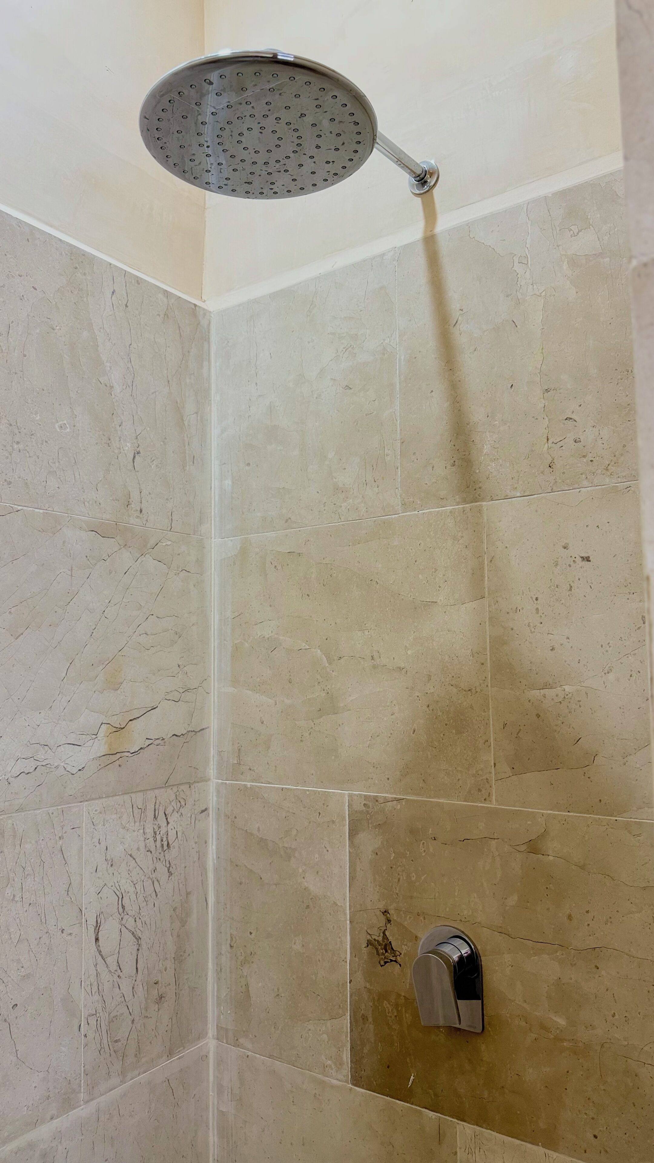Una ducha con cabezal de ducha de mano en un baño con azulejos.