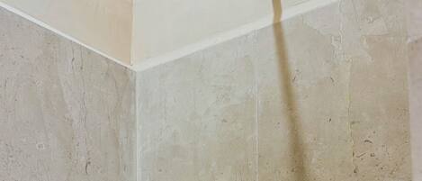 Una ducha con cabezal de ducha de mano en un baño con azulejos.