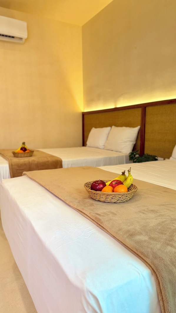 A hotel room with two beds, a fruit basket on the bed, and an air conditioning unit on the wall. - Lapso At Tulum (Tulum)