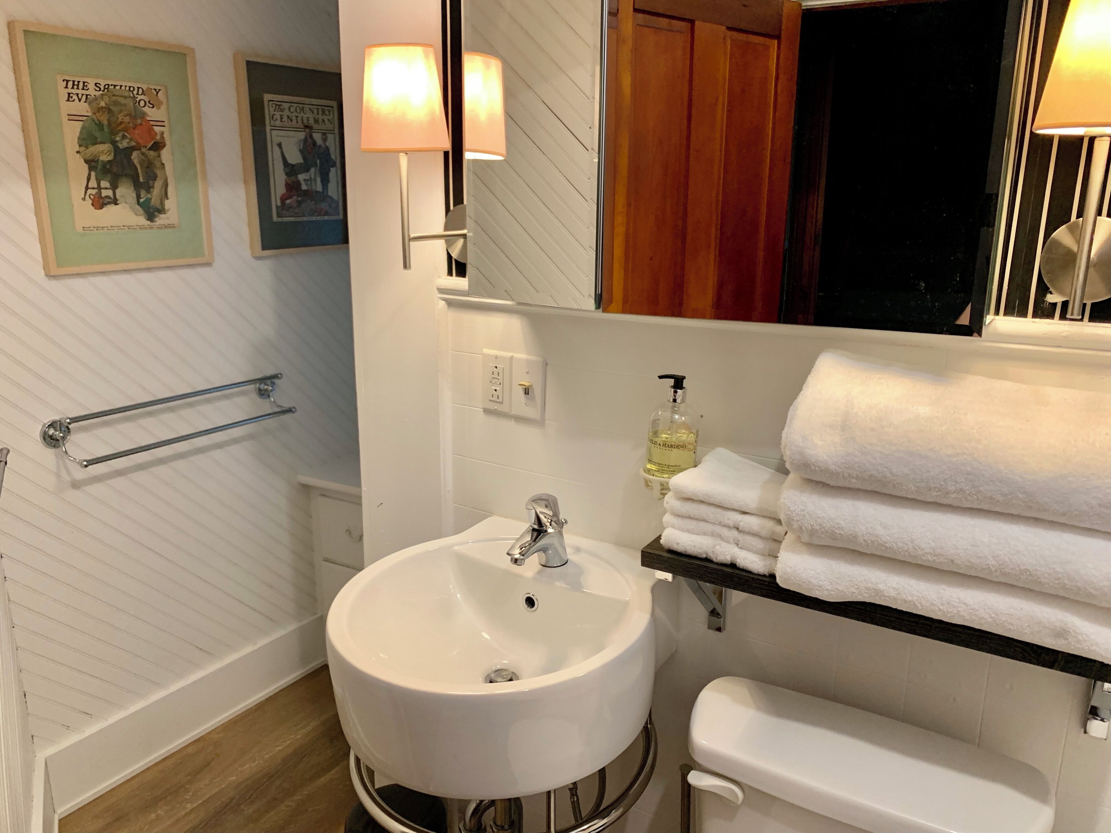 A bathroom with a white sink, a mirror, a towel rack, and a handrail.