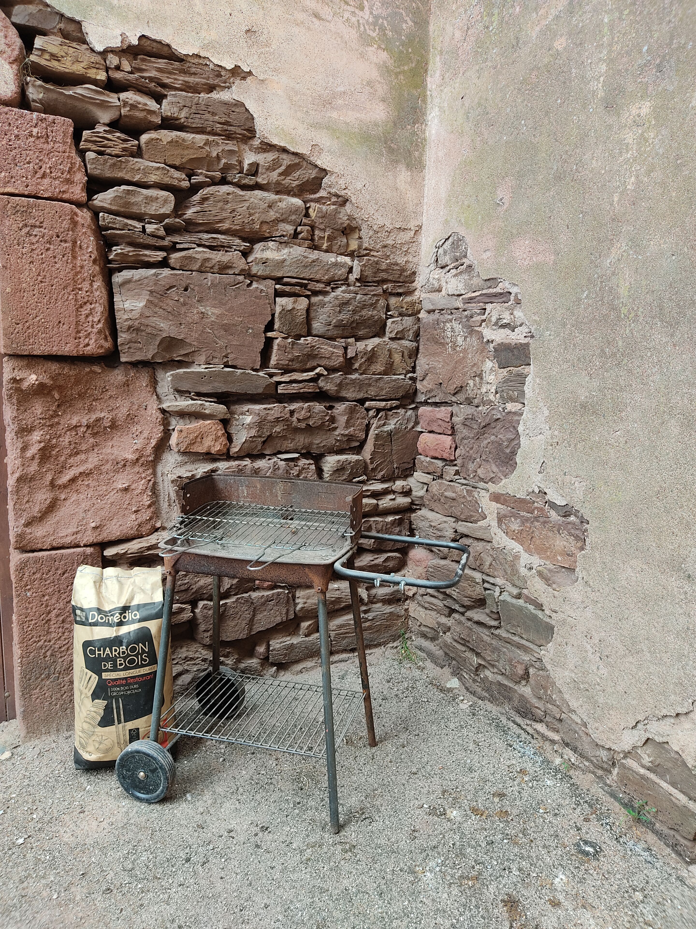 Un muro de piedra con una mesa de metal y una bolsa de carbón.