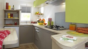 A compact kitchen with a gas stove, a sink, and a window with blinds. - Mobile Home Camping for 4 in Vias (Vias)