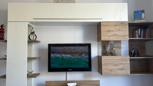 Una sala de estar moderna con un televisor de pantalla plana montado en una pared de madera, rodeada de estanterías empotradas con libros y objetos decorativos.