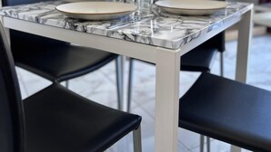 Un comedor moderno con una mesa de mármol, sillas negras y un armario blanco al fondo.