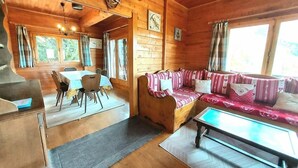 Interno di una baita in legno con zona pranzo, divano e tavolo.