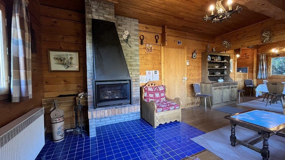 Un intérieur de chalet chaleureux avec une cheminée, des murs en bois, un sol carrelé et un coin repas.