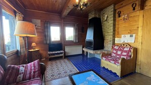 Un accogliente chalet con camino, pareti in legno, pavimento in piastrelle blu, un divano, un tavolo e una lampada.