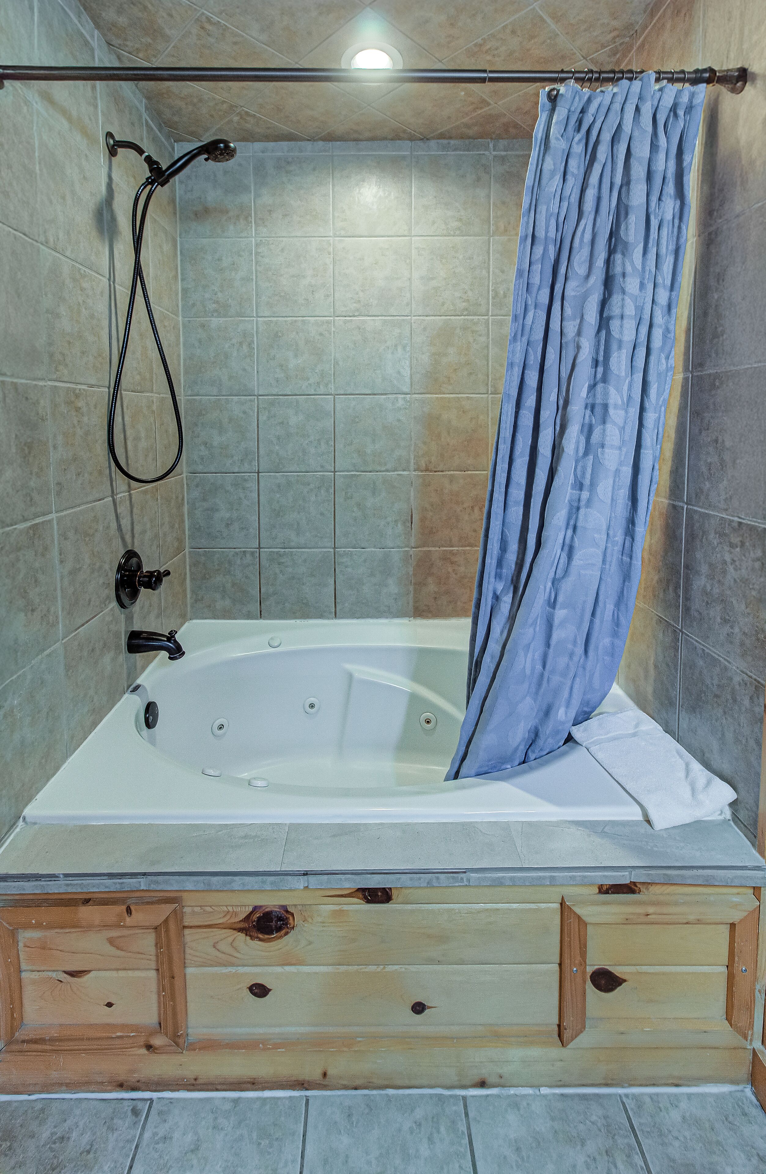 Un baño con bañera, ducha y cajones de madera para almacenamiento.