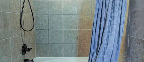 Un baño con bañera, ducha y cajones de madera para almacenamiento.
