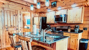 A rustic kitchen with wooden cabinets, a central island with a sink, and a stove.