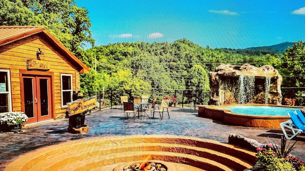 A wooden cabin with a fire pit and a swimming pool.