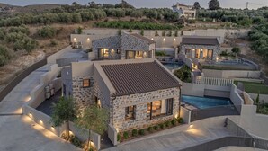 A modern villa with a stone facade, a swimming pool, and a landscaped garden.