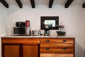 Una cocina equipada con microondas, tostadora, cafetera y un ventanal pequeño.