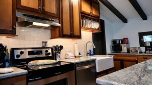 Une cuisine dotée de meubles en bois, d’appareils électroménagers en acier inoxydable et d’un plan de travail en marbre.