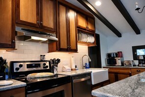 A kitchen with wooden cabinets, stainless steel appliances, and a marble countertop. - Honeymoon Cottage Chateau DuMont (Banner Elk)