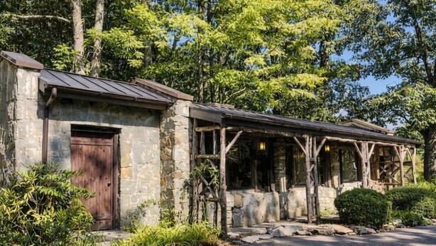 Un bâtiment rustique en pierre, doté d’une porte en bois et d’un porche abrité.