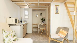 A compact room with a bed, a desk, a chair, a microwave, and a small kitchenette. - Sidi Studio - left side, right in the heart of Budapest, The Sidonies Twins in Seventh (Budapest)