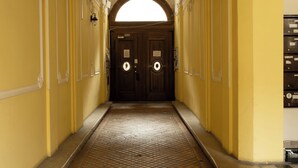 A corridor with a tiled floor, yellow walls, and a wooden door at the end. - Sidi Studio - left side, right in the heart of Budapest, The Sidonies Twins in Seventh (Budapest)