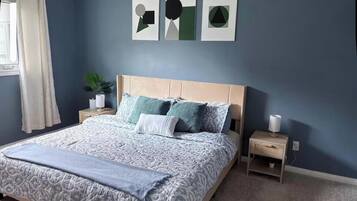 A bedroom with a bed, nightstands, a potted plant, and artwork on the wall.