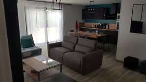 A modern living room with a sofa, a coffee table, and a dining area with a table and chairs. - New house for vacations in Charente-Maritime (Saint-Agnant)