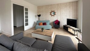 A modern living room with a sofa, a coffee table, a TV stand, and a wall-mounted mirror.