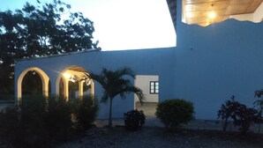 A building with a white exterior, a covered outdoor area with arches, and a palm tree.