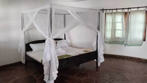 A four-poster bed with a canopy, a single bed sheet, and a green pillow.