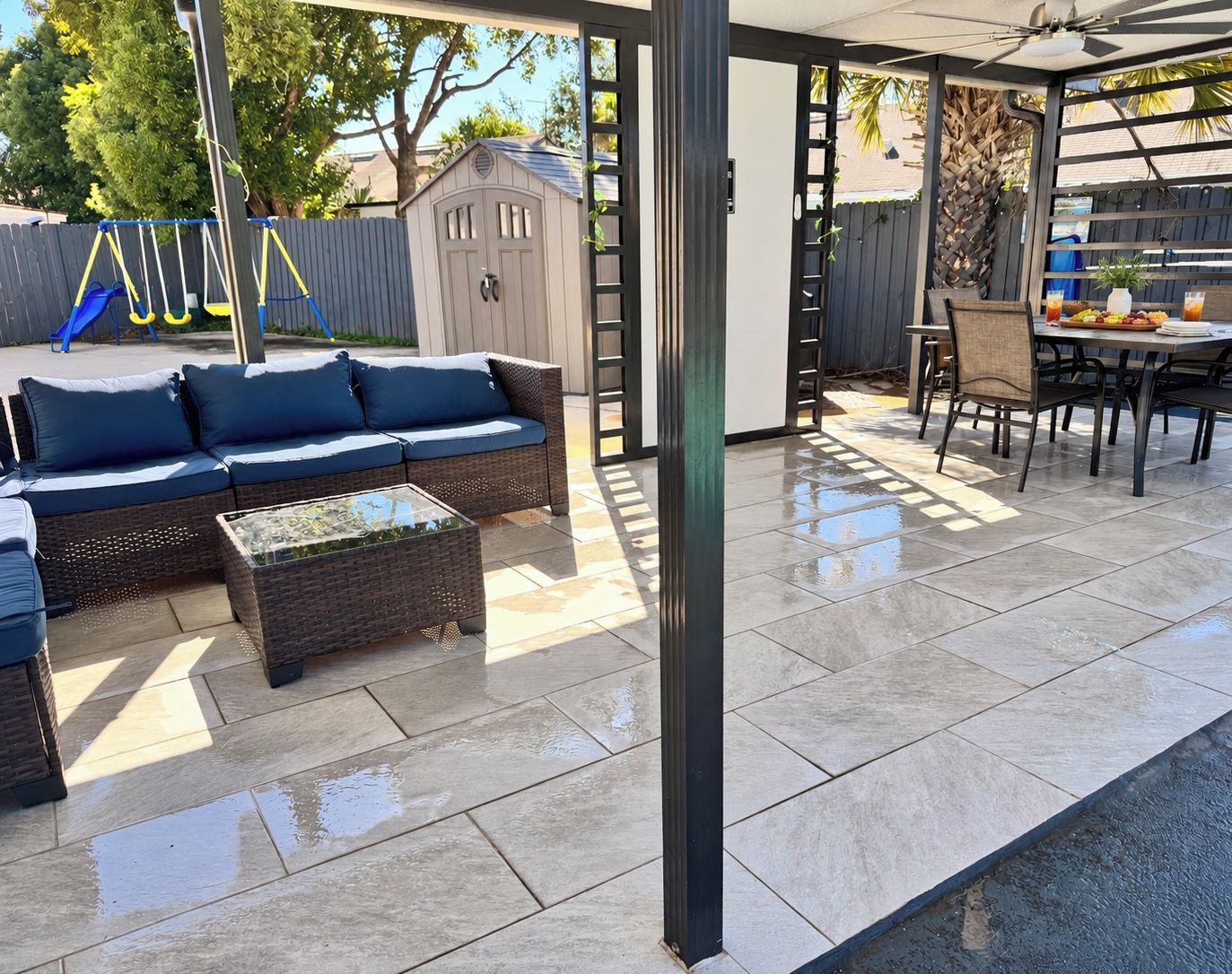 An outdoor patio area with a sofa set, a dining table, and a play structure in the background.