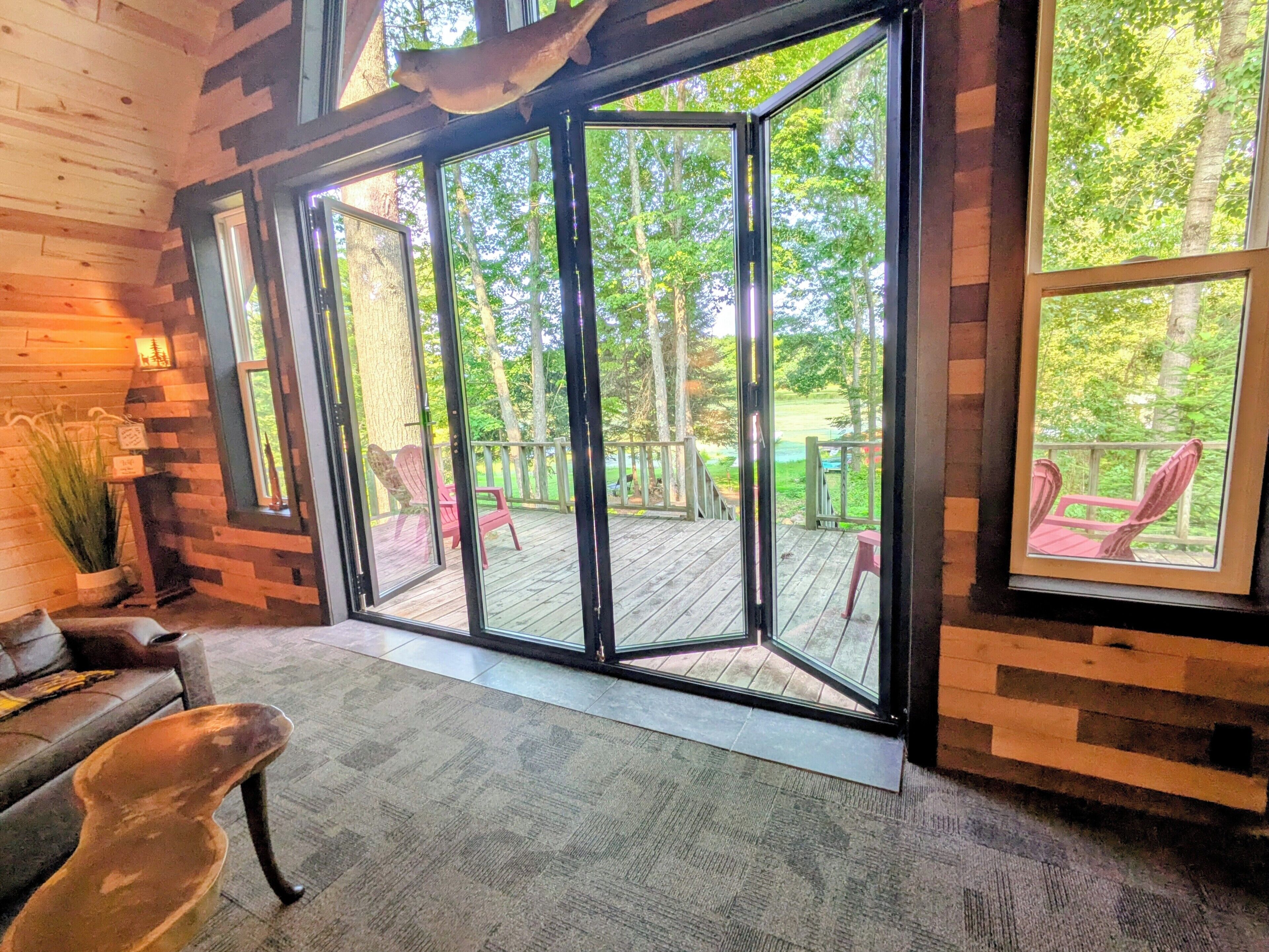 Une pièce dotée d’une grande porte vitrée donnant sur une terrasse extérieure avec des chaises.