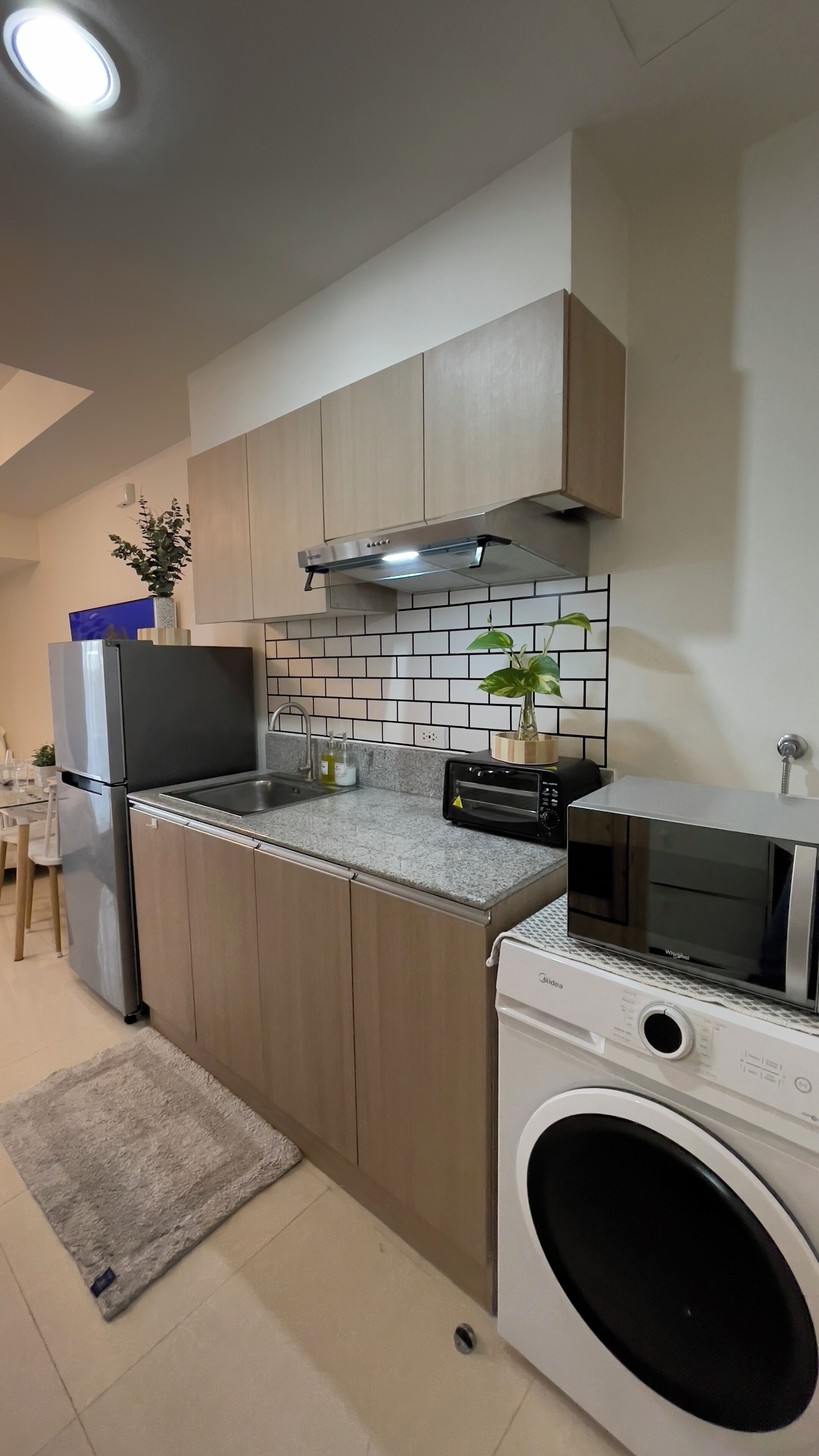 A compact kitchen with a built-in washing machine, a toaster, and a refrigerator.