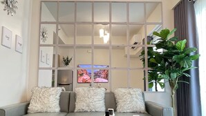 Uma sala de estar moderna com um sofá cinza, uma mesa de centro de madeira e um espelho grande.