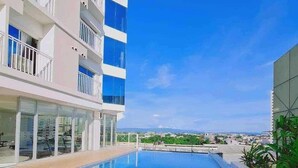 Um hotel moderno com piscina infinita no terraço, guarda-corpos de vidro e vista deslumbrante da cidade.