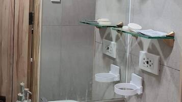 Un baño con un lavabo blanco, un espejo y tres estantes de vidrio con plantas.