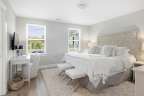 Een slaapkamer met een bed, nachtkastjes, een bureau en een stoel.