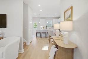 A modern kitchen with white cabinetry, a central island, and a dining area with a table and chairs. - New 3BR Home - Walk to Downtown Belmont - Near CLT - Sleeps 8 (Belmont)