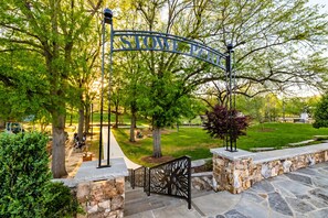 A park entrance with a stone wall, metal gate, and a pathway leading into the park. - New 3BR Home - Walk to Downtown Belmont - Near CLT - Sleeps 8 (Belmont)